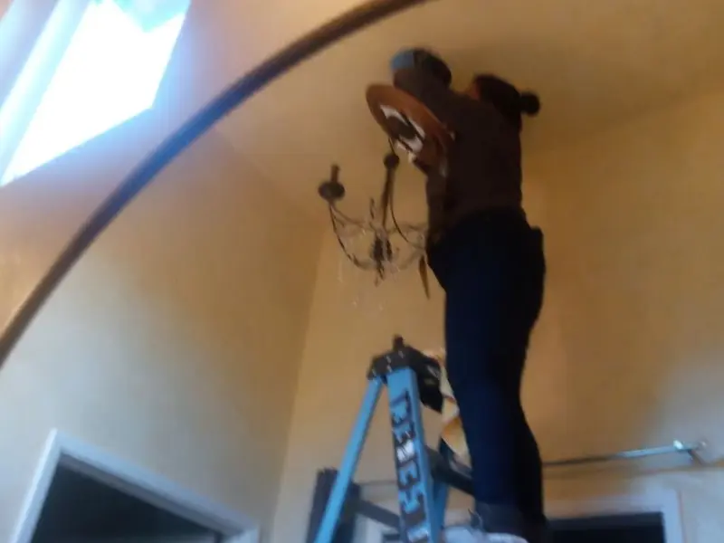 Electrician installing a chandelier in a Fort Lupton residence